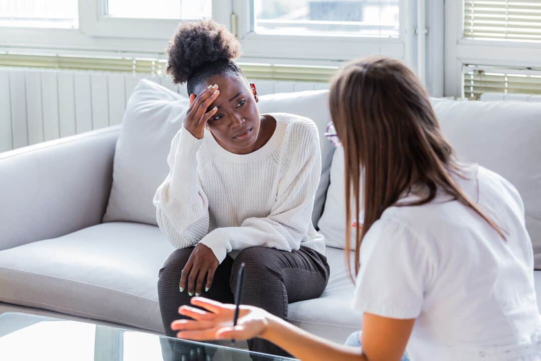 A woman holds her head in her hand while talking to a healthcare provider.