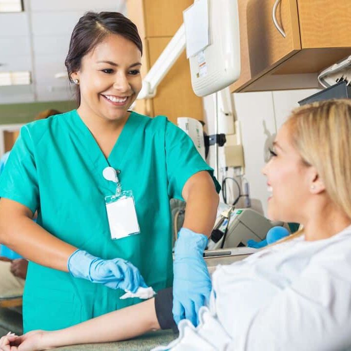 A nurse bandages a woman's arm.