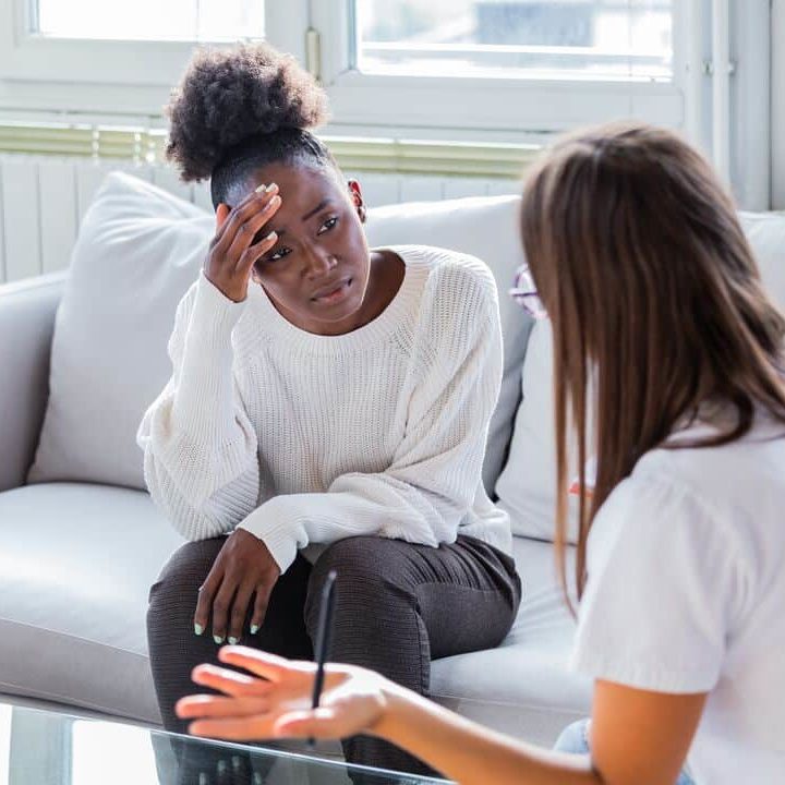 A woman holds her head in her hand while talking to a healthcare provider.